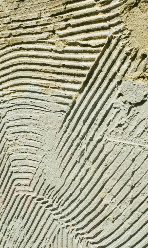 Colle à carrelage étalée et peignée au peigne cranté, sillons croisés