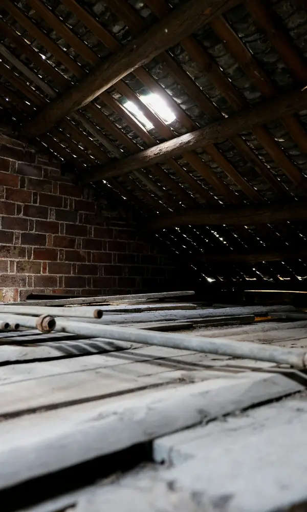 Combles sous charpente, plancher poussiéreux et pignon en briques