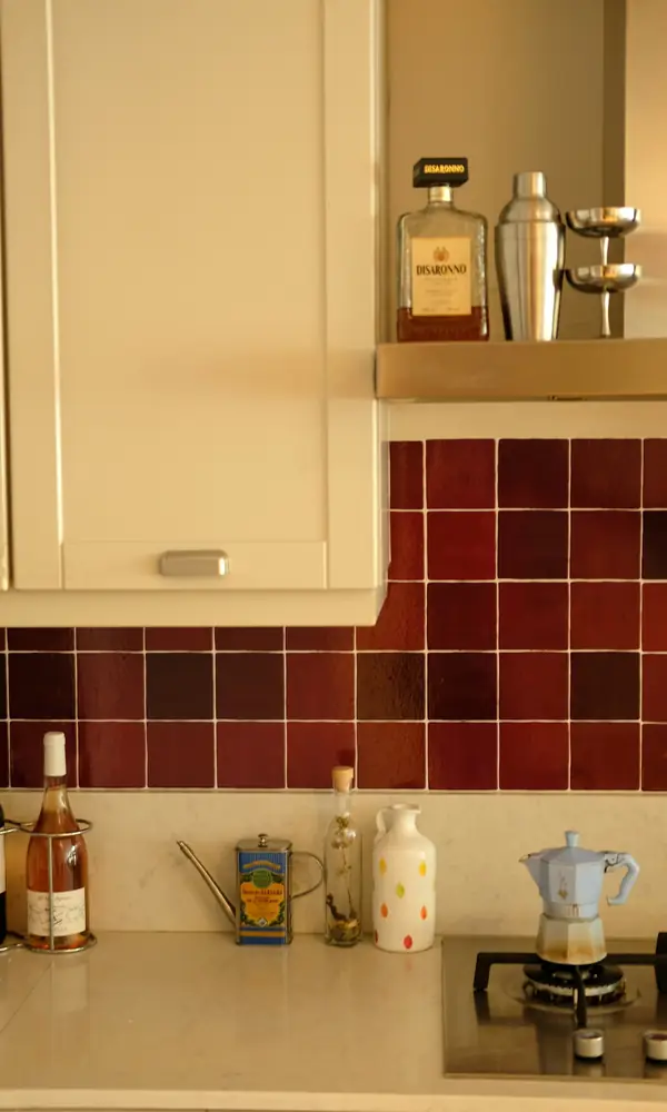 Crédence de cuisine en carreaux carrés rouge sombre sous un meuble haut crème
