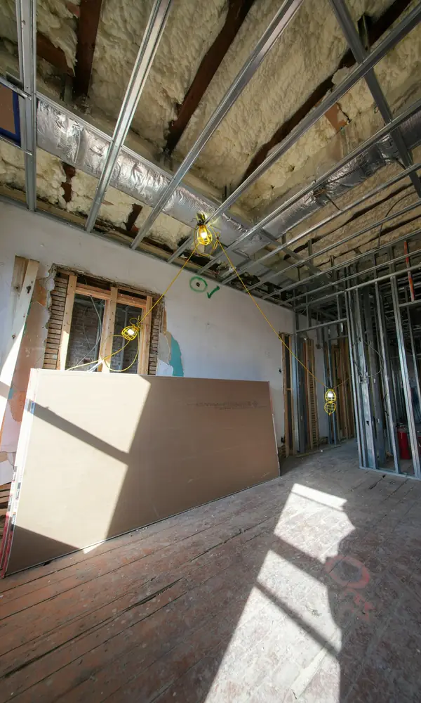 Pièce en travaux : plaques de plâtre posées contre le mur, ossature métallique et isolant au plafond