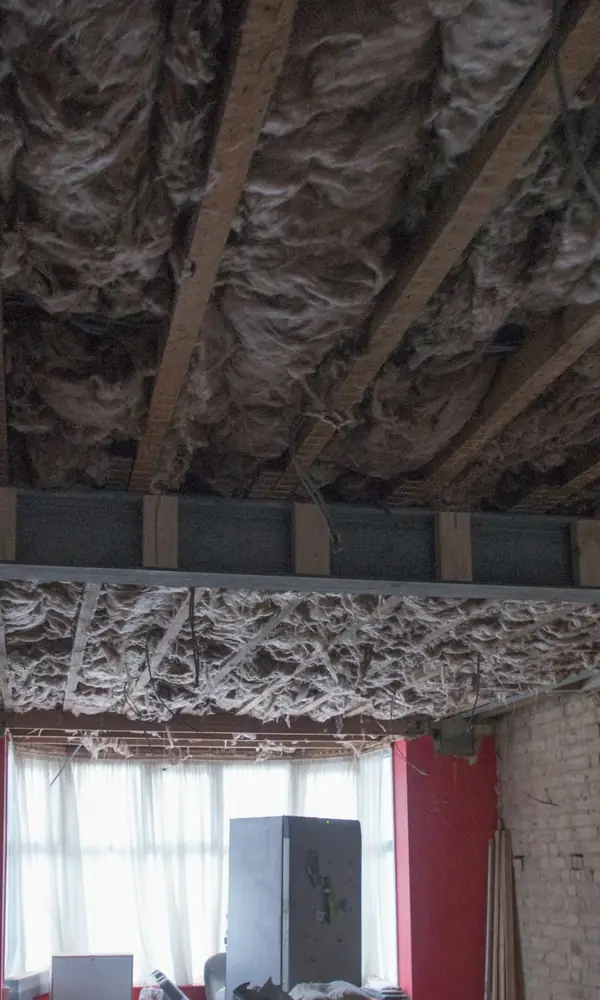 Plafond déposé : solives apparentes et isolant visible au-dessus d’une pièce